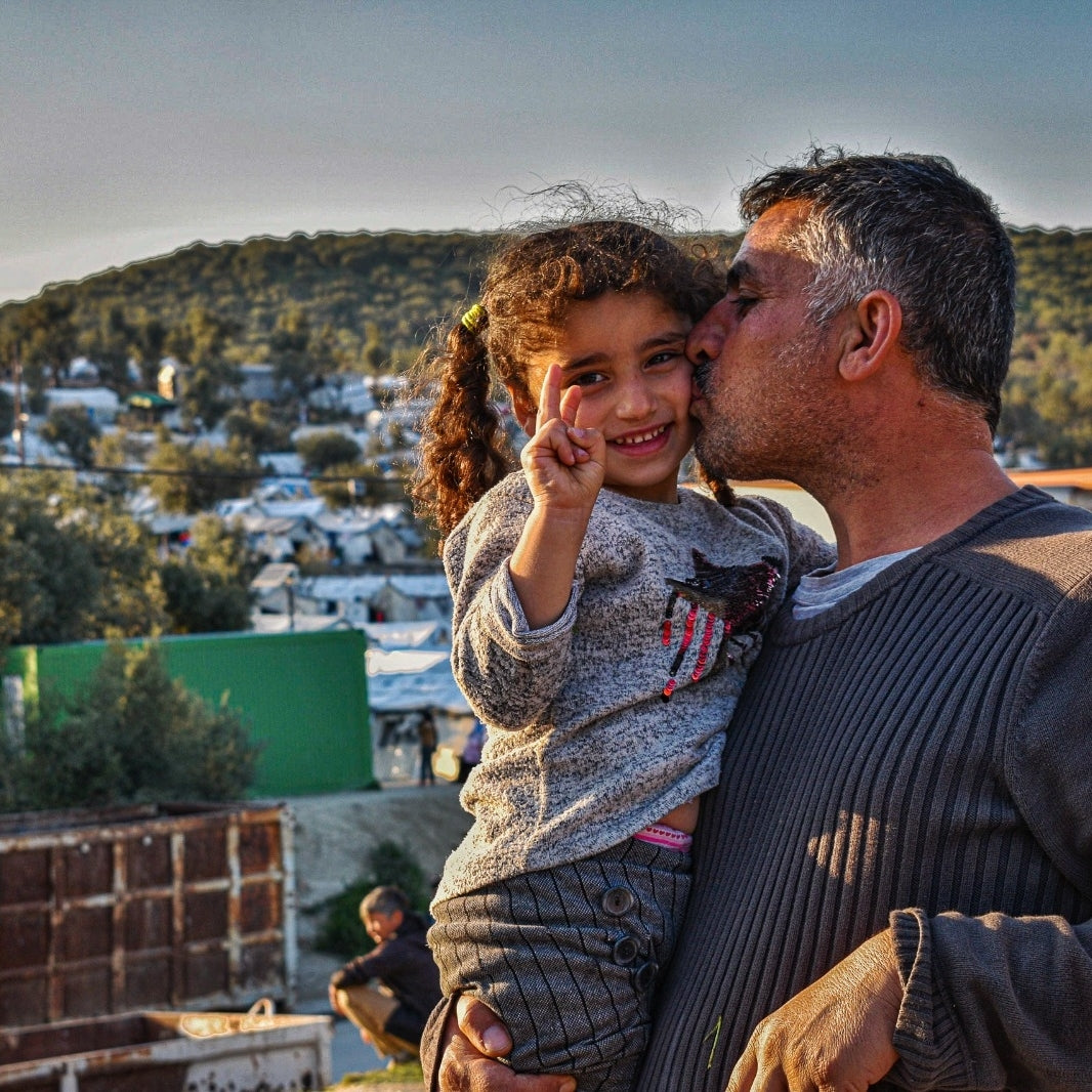 Father kisses his daughter on the cheek as he holds her