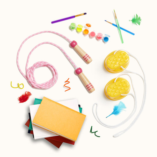 In this image there are a couple of items laying flat such as notebooks stacked on top of each other, a child rope and some painting colours and brushes.